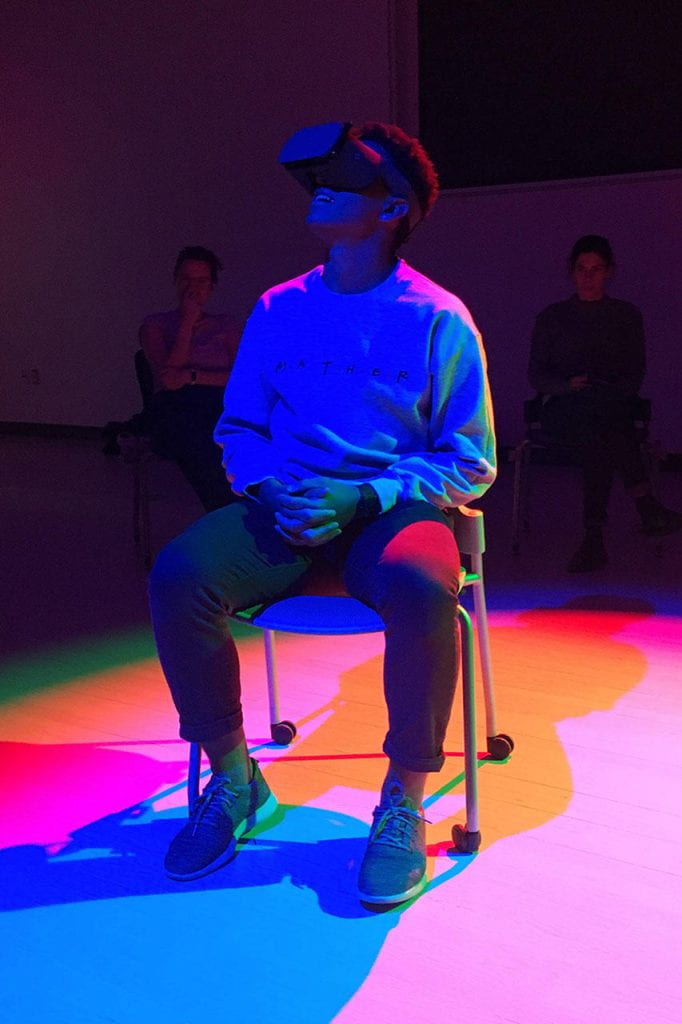 A person sitting on a chair wearing virtual reality goggles